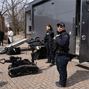 À côté d'un camion spécialisé stationné à l'extérieur, une équipe CBRNE présente un robot de neutralisation de bombes.