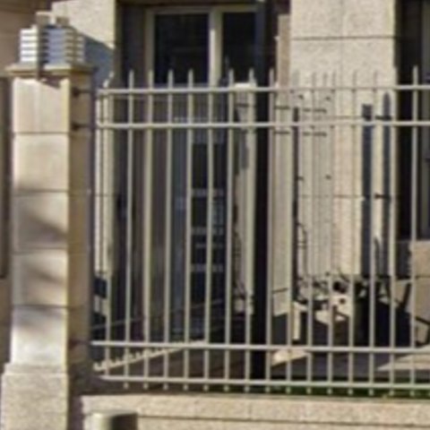 Figure représente une clôture à l'extérieur ou des lattes de clôture métalliques
                        verticales qui sont ancrées à des structures en béton