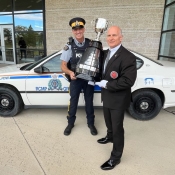 Deux hommes tiennent le trophée, la Coupe Grey, devant un véhicule de police