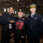 L'ancien joueur de football montre sa bague de championnat en se tenant à côté d'un policier en uniforme et d'un homme portant le chandail des REDBLACKS.