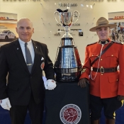 Le gardien de la Coupe Grey et un officier en tunique rouge posent avec la Coupe Grey