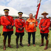 Des membres de la <abbr>GRC</abbr> de l'Île-du-Prince-Édouard en tunique rouge se tiennent aux côtés du membre Mi'kmaq et sénateur canadien Brian Francis lors du pow-wow d'Abegweit.