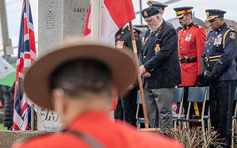 Devant un monument aux morts, deux agents de la GRC, entourés d'autres personnes, s'inclinent.