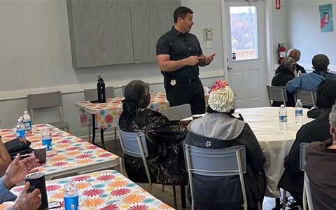 Un officier de police fait une présentation devant une salle.