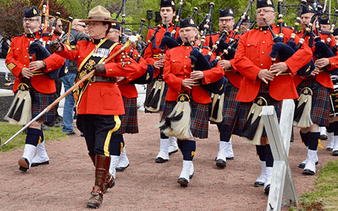 Des membres du Corps de cornemuses et de tambours de la GRC participent à un défilé tout en jouant de la cornemuse.