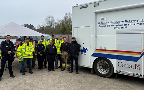 Des agents de la GRC et des pompiers se tiennent à côté du véhicule de l’équipe de récupération sous-marine de la GRC.