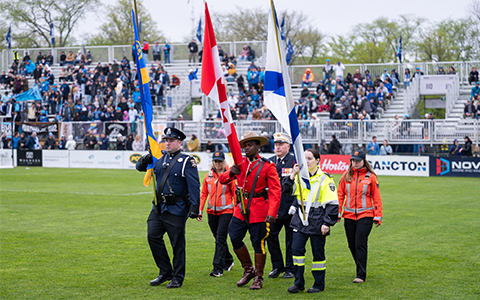 Des premiers intervenants, dont un agent de la GRC en tunique rouge, portent des drapeaux sur un terrain.