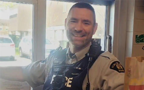 Un agent de la GRC sourit à la caméra dans le service à l’auto d’un McDonald’s.