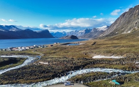 Prise de vue aérienne d'un terrain rocailleux près d'un lac glaciaire encadré de montagnes enneigées.