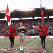 Deux membres de la GRC tiennent des drapeaux sur un terrain de football.