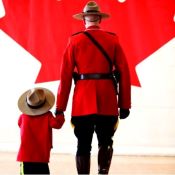 Un agent en tunique rouge marche avec un enfant en tunique rouge.