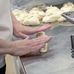 Un boulanger roule la pâte et la place sur une plaque à pâtisserie.
