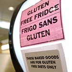 Une affiche au haut d'un réfrigérateur indique qu'il contient de la nourriture sans gluten.