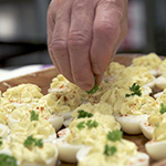 Un cuisinier garnit un plateau d'œufs à la diable.