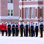 Des cadets sont dans la Cour d'honneur. Chaque troupe porte un uniforme du jour différent.
