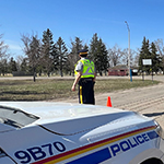 Un cadet portant un gilet de haute visibilité est sur la route devant une voiture de police.