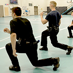 Des cadets font des fentes marchées dans un gymnase.