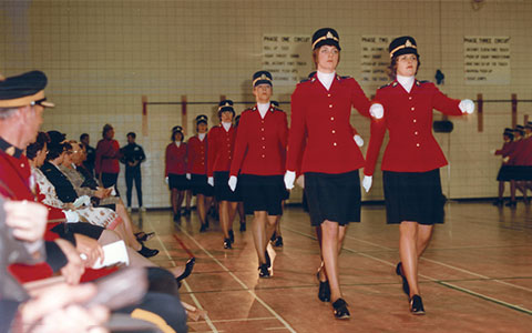 Femmes en uniforme défilent dans un gymnase.