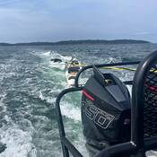 Photo de kayaks vides remorqués derrière un bateau de la GRC.