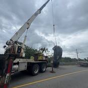 Le VUS volé, pendu par son essieu arrière, est rapporté sur la chaussée par une grue. Une dépanneuse se trouve derrière le VUS.