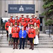 Photo de groupe de certains des récipiendaires de la médaille de la Division M, certains portant l'uniforme de tunique rouge, debout en quatre rangées, avec la commissaire du Yukon, Adeline Webber, debout au milieu de la première rangée.