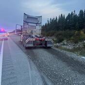 Un camion de transport dans l’accotement en gravier d’une route. Des véhicules de la GRC sont devant le camion et leurs gyrophares sont allumés.