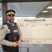 Un agent de la GRC de Terre-Neuve-et-Labrador se tient à côté d'un tableau d'affichage lors de la collecte de sang « Sirens for Life ».