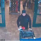Suspect poussant un panier et sortant par la porte principale de Cabelas.