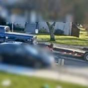 Une camionnette bleue vue du côté conducteur. Le véhicule tire une remorque à plateau vide et roule dans une rue secondaire.