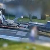 Une camionnette bleue vue du côté passager. Le véhicule tire une remorque à plateau sur laquelle se trouve une chargeuse Bobcat volée, et il roule dans une rue secondaire.