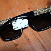 Une paire de lunettes de soleil de marque Chanel sur un plancher de bois dont l’étiquette indique un prix de 1 140 $.