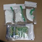 Sacs de preuve scellés contenant trois emballages de poudre blanche et un emballage contenant de la monnaie canadienne.