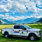 Camionnette de police stationnée dans un champ avec le mont Currie en arrière-plan.