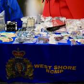 Table exposant la drogue, les répliques d’armes de poing, les couteaux et l’argent saisis par les policiers