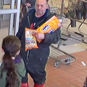 Photo d’un suspect marchant dans l'allée d’entrée et de sortie d’un supermarché avec un article alimentaire et une boîte de boissons gazeuses.