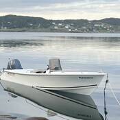 Un bateau blanc, équipé d’un moteur hors-bord Yamaha, est amarré dans l’eau. Le numéro d’identification à l’avant du bateau indique « NL2597915 » et l’inscription « Ocean Fisher » figure sur la poupe.