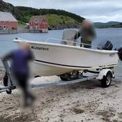 Un bateau blanc repose sur une remorque galvanisée sur une rampe de mise à l’eau.