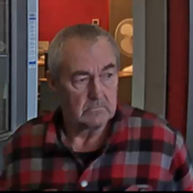 Un homme avec une chemise à carreaux rouges et gris sortant d’une banque.
