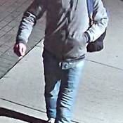 Photo d’un homme marchant sur le trottoir, vêtu d’un chandail à capuchon et d’un jean bleu, et portant un sac à dos.