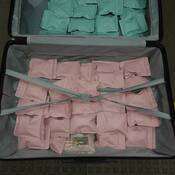 Des paquets verts et roses contenant de la méthamphétamine se trouvant dans une valise ouverte.