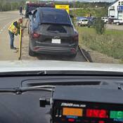 Un conducteur de dépanneuse charge une Chevrolet Trax noire sur son véhicule tandis qu’un radar monté sur le tableau de bord d’un véhicule de la Patrouille routière de la C.-B. affiche une vitesse de 142 km/h