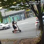 Image provenant de la caméra d’intervention d'un policier montrant un jeune de petite taille portant un short, un t-shirt, un casque surdimensionné et de grosses chaussures, conduisant une trottinette électrique dans une circulation dense