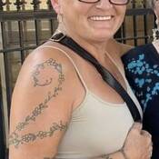 Tania Langley avec tatouage d’une vigne et d’une fleur sur le bras
