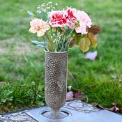 Un vase en bronze contenant des fleurs, posé sur une pierre tombale.