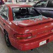 Un véhicule Subaru rouge dont la lunette arrière est fracassée.