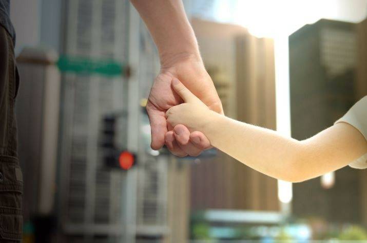 Man holding the hand of a young girl in a city.