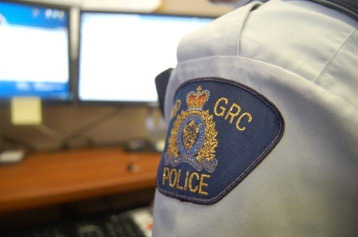 A uniformed RCMP officer sits at a computer. 