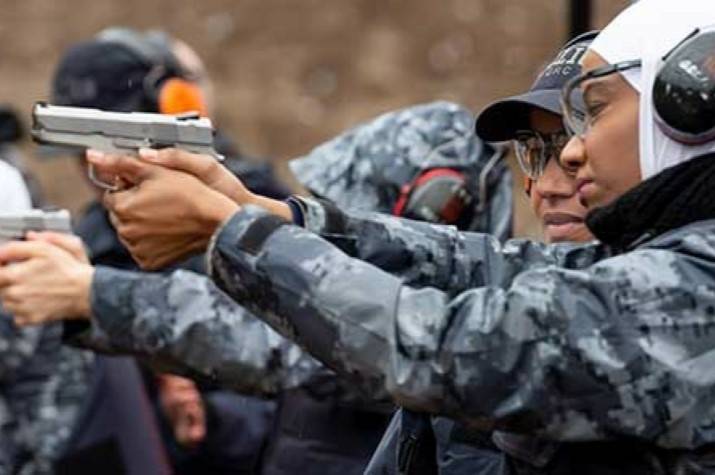 Woman points gun during firearms training at a shooting range.