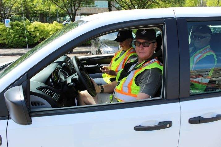 A man and a woman sit in the front seats of a vehicle. Another man sits in the back seat.