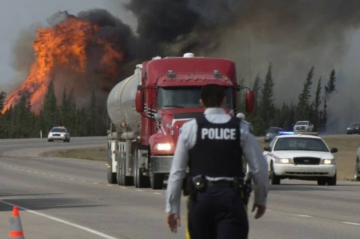 RCMP officer walks on road near forest fire.